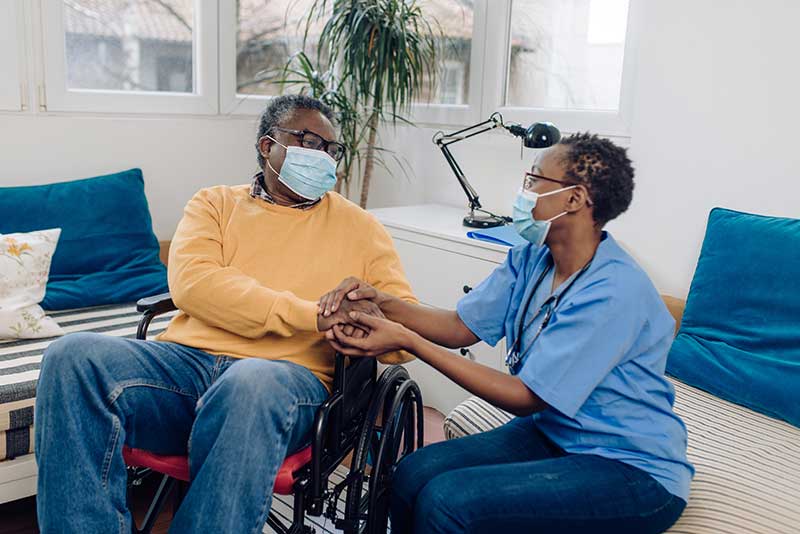 senior man in a wheelchair having support from his home caregiver