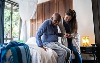 Home caregiver helping a senior man standing up at home